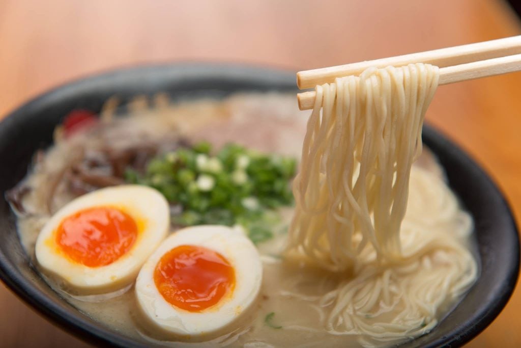 Chopsticks holding noodles from bowl at Hakata Ikkousha Ramen in Torrance