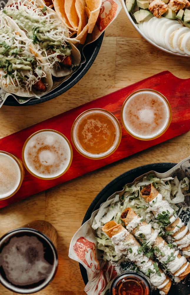 Tablescape of beverage flight and surrounding Mexican dishes