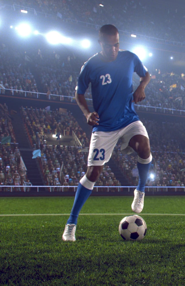 Soccer player dribbling soccer ball on the stadium field during a game