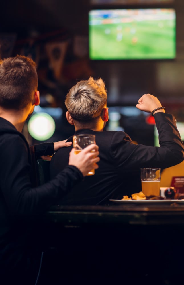 Fans cheering on their team watching a game in a bar and restaurant