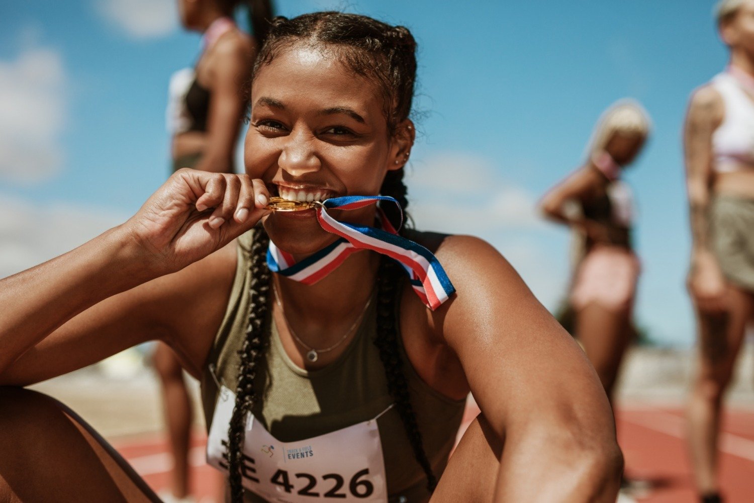 Female athlete playfully biting gold medal after win