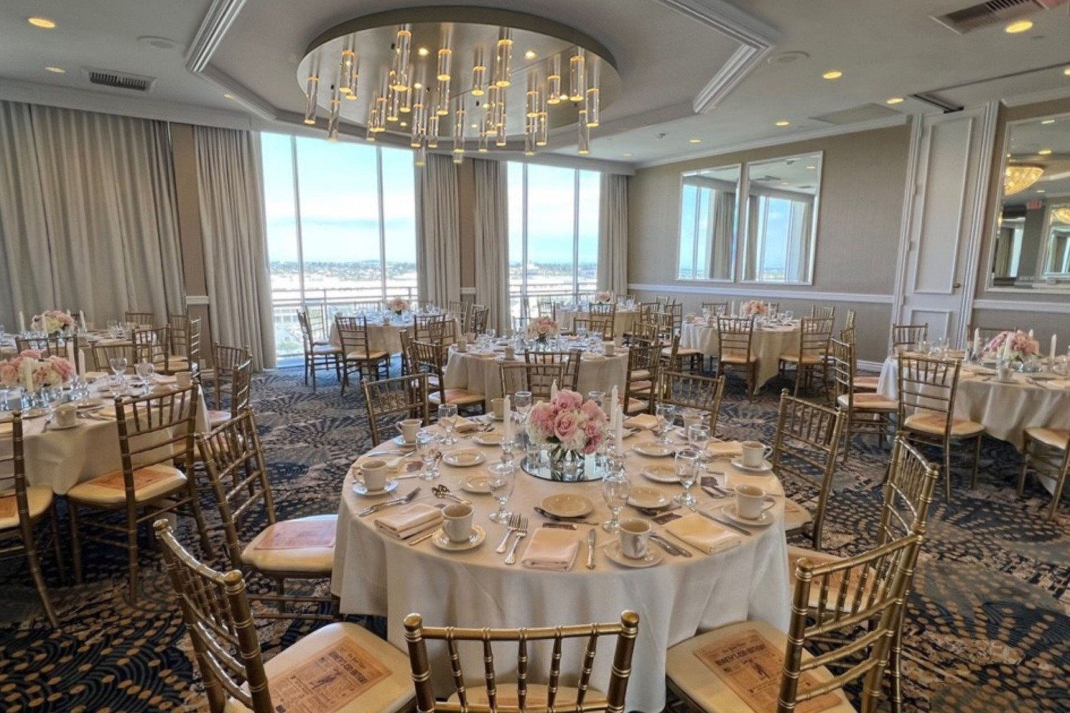 Image of ballroom decorated with tables, chairs, flowers, candles and dining ware for an event