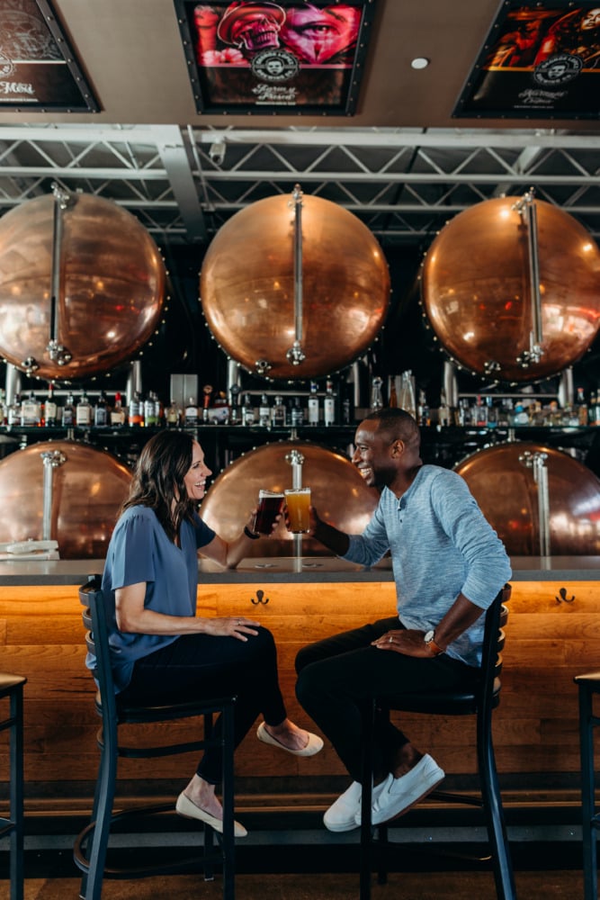 Couple at brewery cheersing with beer and smiling