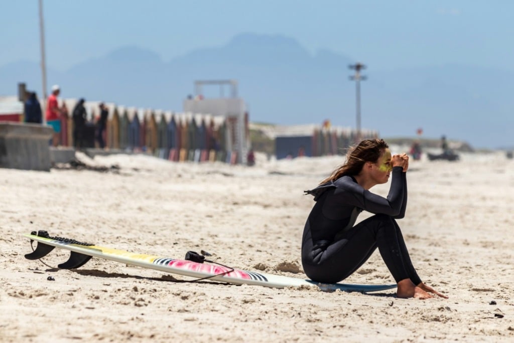 Surfer sitting on beach in wetsuit